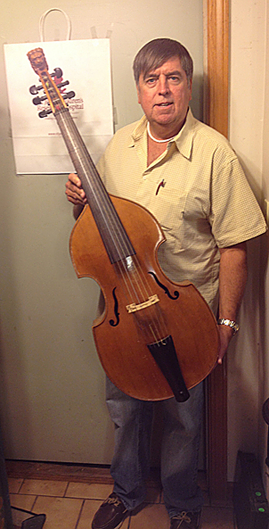 Auctioneer Tim Chapulis holds an antique viola de gamba, a musical instrument larger than a violin but smaller than a cello. Tim’s Inc. image.